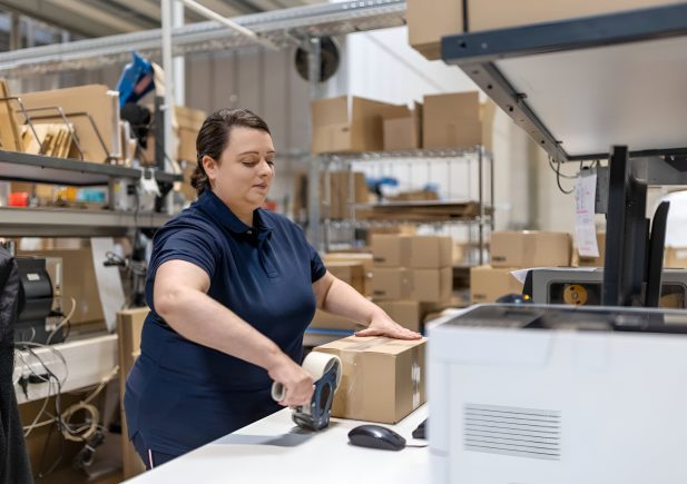 Woman worker packing delivery package for shipping at warehouse